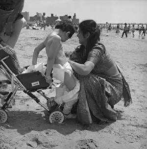 1982 Prints: Indian mother changing her son's diapers on the beach of Coney Island