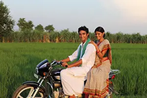 Villager Prints: Indian rural couple riding on a motorcycle in the field
