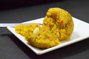 Rajasthani Prints: Indian Sweet Moti Choor Laddu in White Plate Top View on Black Background Close-Up Stock Photograph Image