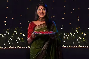 Occasions Prints: Indian woman in green saree holding a plate with diya on the occasion of Diwali