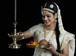 Femininity Prints: Indian woman in traditional clothing lighting an oil lamp