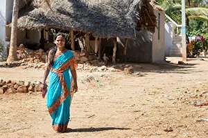 Villager Prints: Indian woman wearing a blue sari walking in a rural indian village. Andhra Pradesh, India