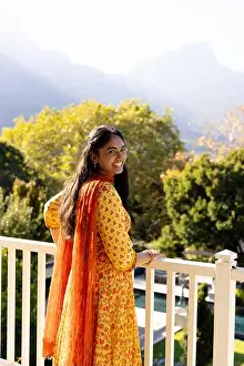 Indian People Prints: Indian woman in yellow dress, standing on balcony outdoors; enjoying mountain view