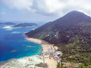 Indonesia Anambas Islands - Drone view Telaga Island coast line with village and vulcano
