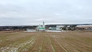 Cold Weather Prints: Initial winter. Clip.View from a drone on a landscape with snowy grass in a field where there is a temple with a golden