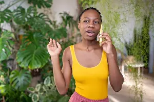 Gossip Prints: Interested black woman takes break for chatting smartphone have pleasant talk surround by plants