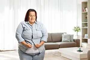 Irritated Prints: Irritated overweight woman at home trying to button a denim shirt