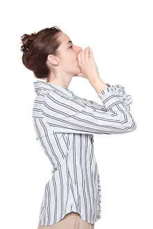 Megaphone Prints: Isolated studio shot of the side view of a Caucasian woman using her hands as a megaphone as she yells