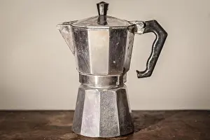 Maker Prints: Isolated used vintage moka pot on a white background standing on a retro wooden table