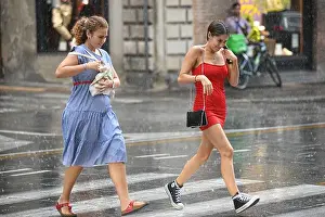 Millennials Prints: Italian young girls crossing the street in the rain. Via Ugo Bassi, Bologna, Italy