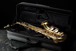 Orchestra Prints: Jazz. Golden saxophone in case on black textured table