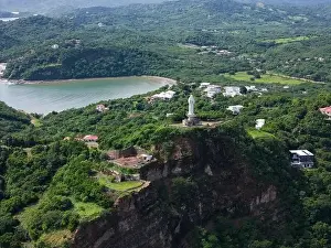 San Juan Prints: Jesus statue on rock cliff in green hill landscape aerial drone view