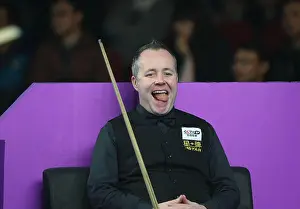 Championship Prints: John Higgins of Scotland sticks out his tongue as he watches Joe Swail of Northern Ireland playing a shot in their