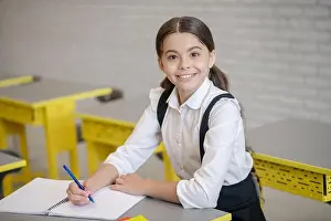 Explaining Prints: Joyful girl in school uniform sitting at desk