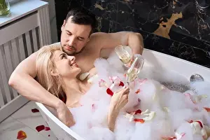 Honeymoon Prints: Joyful newlyweds enjoying champagne in a bathtub with rose petals