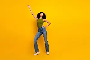 Flair Prints: Joyful young woman in trendy outfit posing against bright yellow background with confident energy