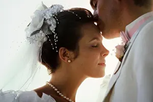 Tenderly Prints: Just married, new Caucasian husband kisses his beautiful young wife on the forehead