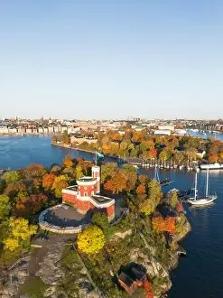 Swedish Flag Prints: Kastellholmen red castle on island with Stockholm skyline in the background on a sunny autumn morning with turning