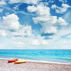 Two kayaks on sea edge. Incredible blue sky with fluffy clouds on background. Summer time