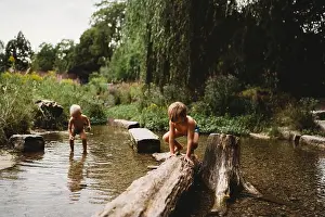 Barefoot Prints: Kids playing in the water in stream by rocks and logs in summer