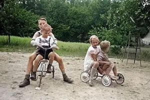 Kinder Prints: Kinder spielen mit Roller und Dreirad auf einem Spielplatz