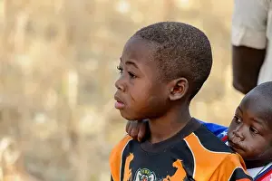 Nigeria Prints: KOUTAMMAKOU, TOGO - JAN 13, 2017: Unidentified Togolese little boy carries his brother on his back in the village
