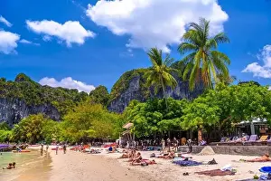 Cliff Mountain Prints: KRABI, THAILAND- MARCH 2018: People sunbathing among coconut palms on Railay beach west