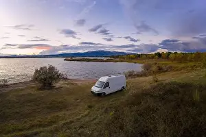 Lake drone aerial view of a camper van with solar panel living van life mountain panorama landscape at sunset in