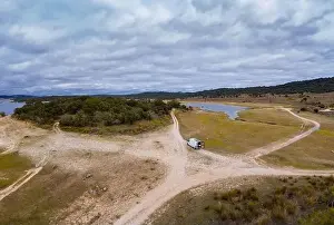 Camper Van Prints: Lake drone aerial view of a camper van with solar panel living van life mountain panorama landscape at sunset in Idanha