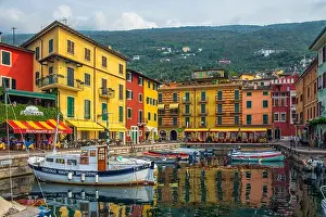 Garda Prints: Lake Garda boardwalk with houses, tourists and boats in Torbole, Italy