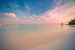 Landscape of paradise tropical island beach, water villas and bungalows with sunset sky. Luxury summer holiday and vacation, tranquil beach view