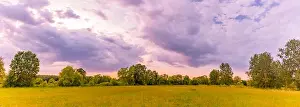 Landscape of sunrise over mountain. Dramatic clouds and colorful sky over green trees and summer meadow flowers