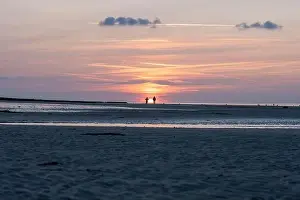 Yellow Buoy Prints: Langrune-Sur-Mer, France - 07 21 2023: View a man and a woman looking at the sunset on the beach
