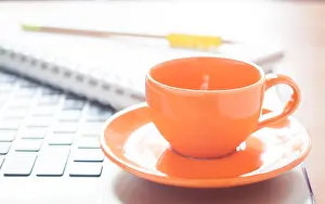 Coffee Cup Prints: Laptop with coffee cup and notepad on desk, stock photo