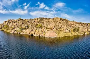 Among the large boulders, a smooth shining stream flows in the evening warm light in picturesque Ukraine