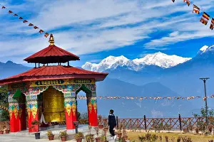 Sikkim Prints: A large Buddhist prayer wheel with a beautiful mountain landscape backdrop of Mt