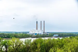Overcast Prints: A large riverside power plant sits across a wide river behind a band of green spring trees