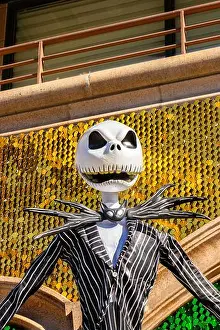 Grinning Prints: A large sculpture of a grinning skeleton jack skellington in a striped suit with a glittering colorful backdrop in an