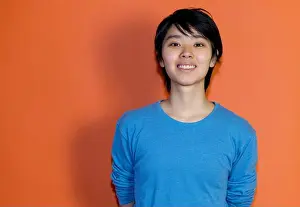 Refugee Prints: Laughing chinese young adult man with blue shirt isolated on orange background