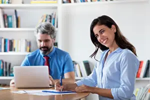 Advisor Prints: Laughing mexican businesswoman with colleague at desk at office of start up company