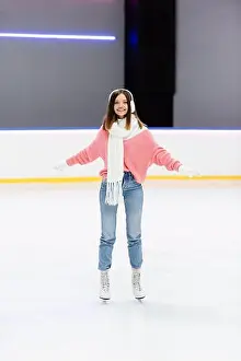 Knitted Prints: full length of cheerful woman in white ear muffs and scarf skating with outstretched hands on ice rink