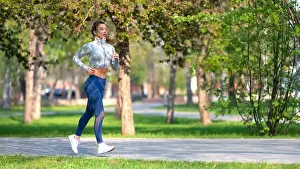 Green Trees Prints: Full length photo of a woman running in park in early morning