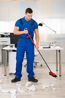 Cleaner Prints: Full length portrait of smiling janitor holding broom while standing in office