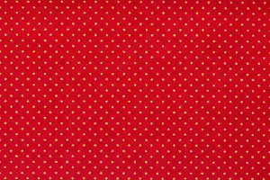 Aligned Prints: Still life close up detail of a bright red piece of paper with aligned white polka dots and texture