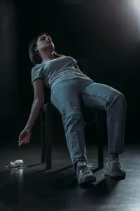 Desperation Prints: lifeless woman on chair committed suicide by overdosing pills on dark background with lighting