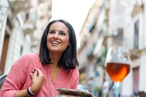 Forties Prints: Lifestyle portrait of a mid-aged woman drinking red wine and chatting with friends on a coffee table outdoors