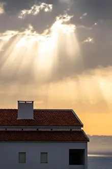Blessed Prints: Light beams from sun called crepuscular rays hover house roof