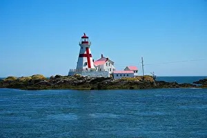 Ocean Beach Prints: A lighthouse with a red roof on a small island
