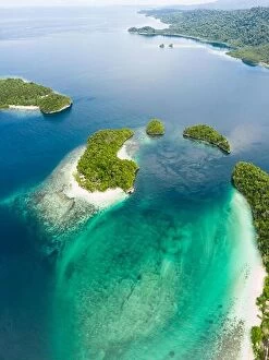 Aerial Landscape Collection: Limestone islands, surrounded by coral reefs, lie scattered throughout the Raja Ampat seascape