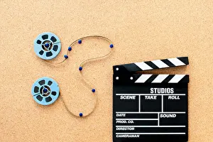 Reel Prints: Two little blue movie reel connected with filmstrip path on wooden cork board